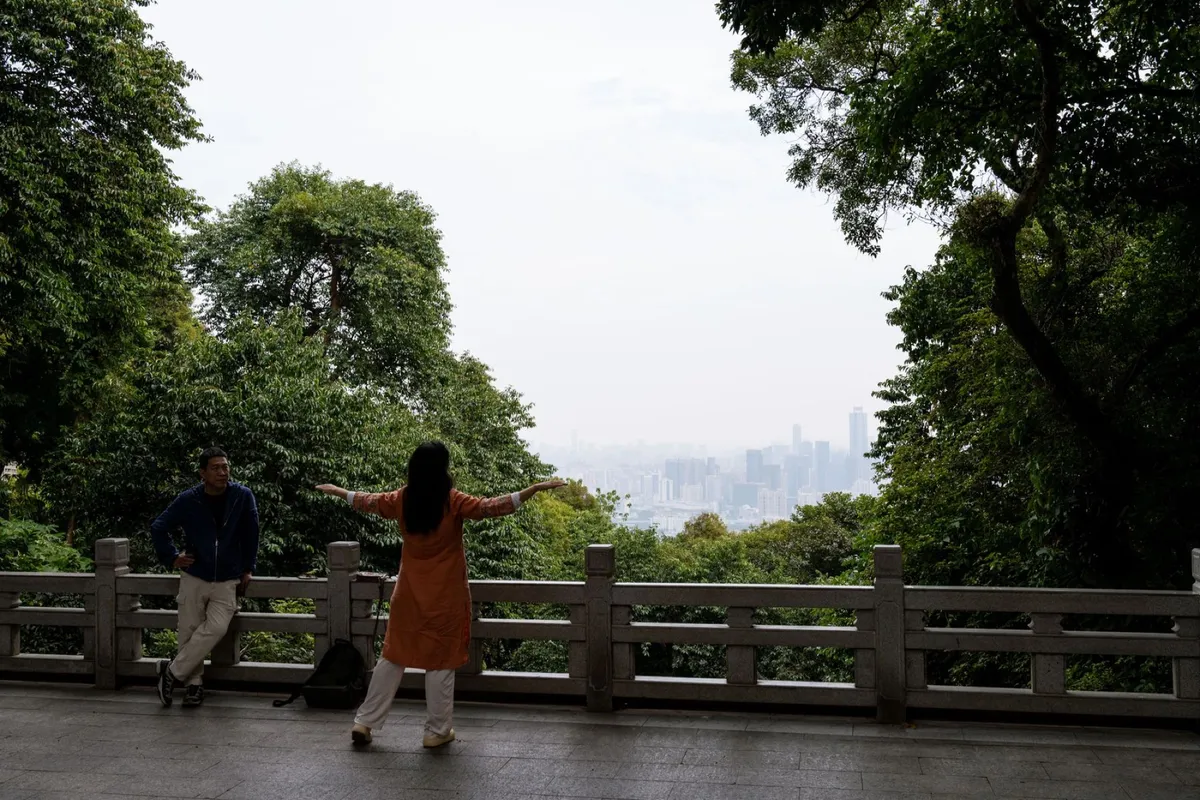 Visitors looking out over Guangzhou's hazy skyline from a stone viewpoint on Baiyun Mountain