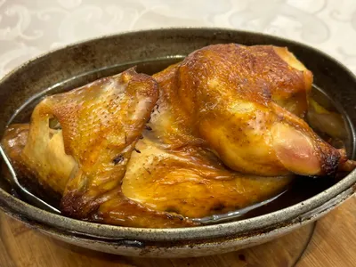 A whole braised Beggar's Chicken served in a dish, skin glossy and golden-brown