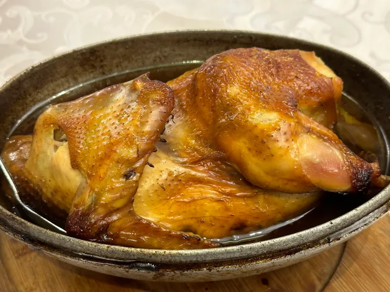 A whole braised Beggar's Chicken served in a dish, skin glossy and golden-brown