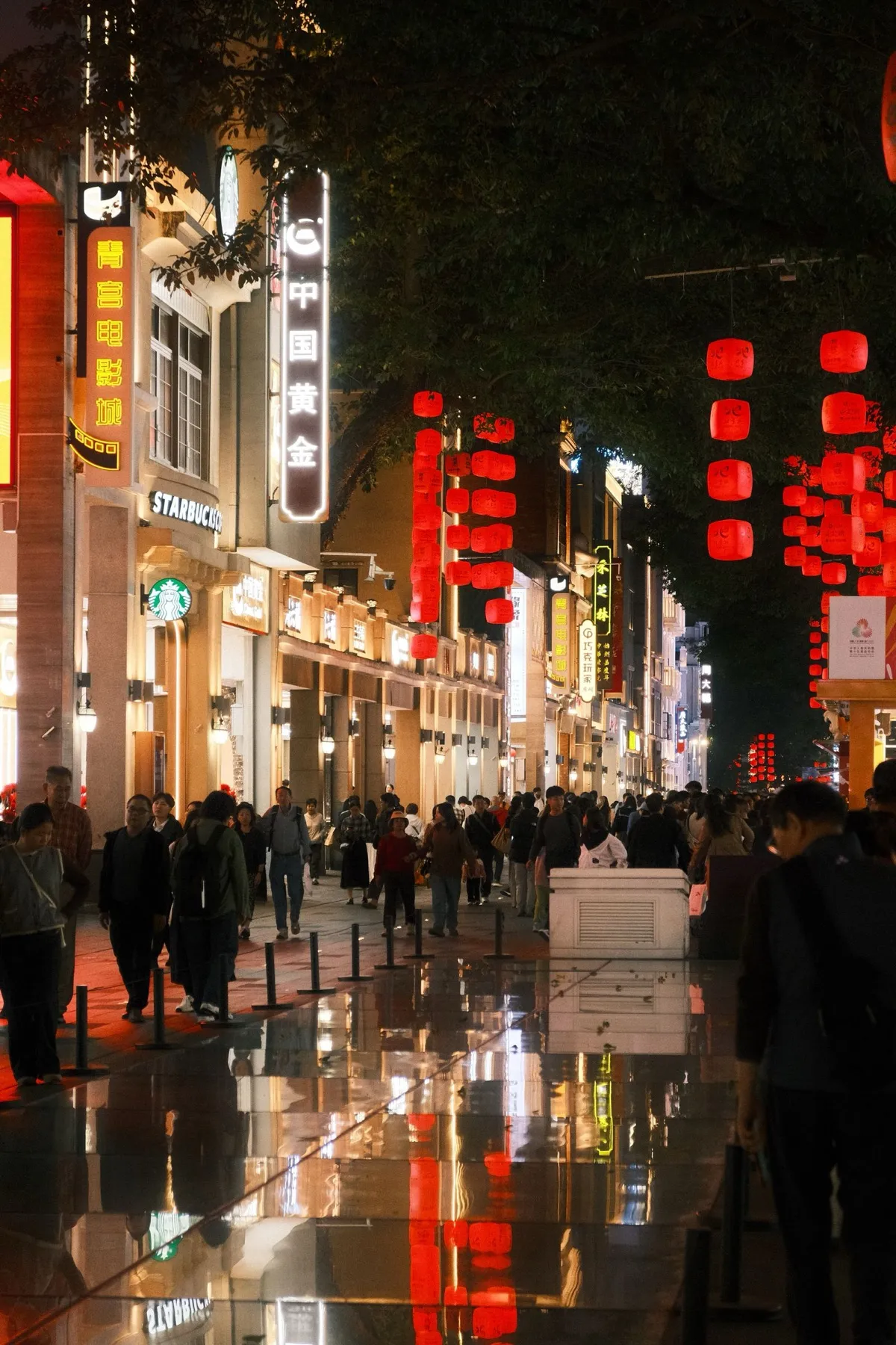 A crowded pedestrian shopping street at night lit with red lanterns and neon signs on Beijing Road