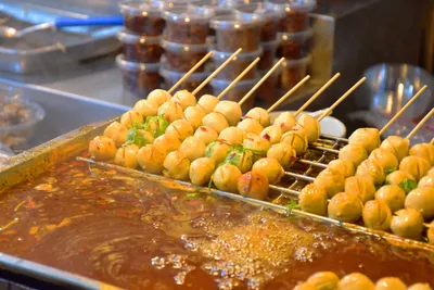 Skewers of food cooking in a spicy chili broth at a Chongqing street stall