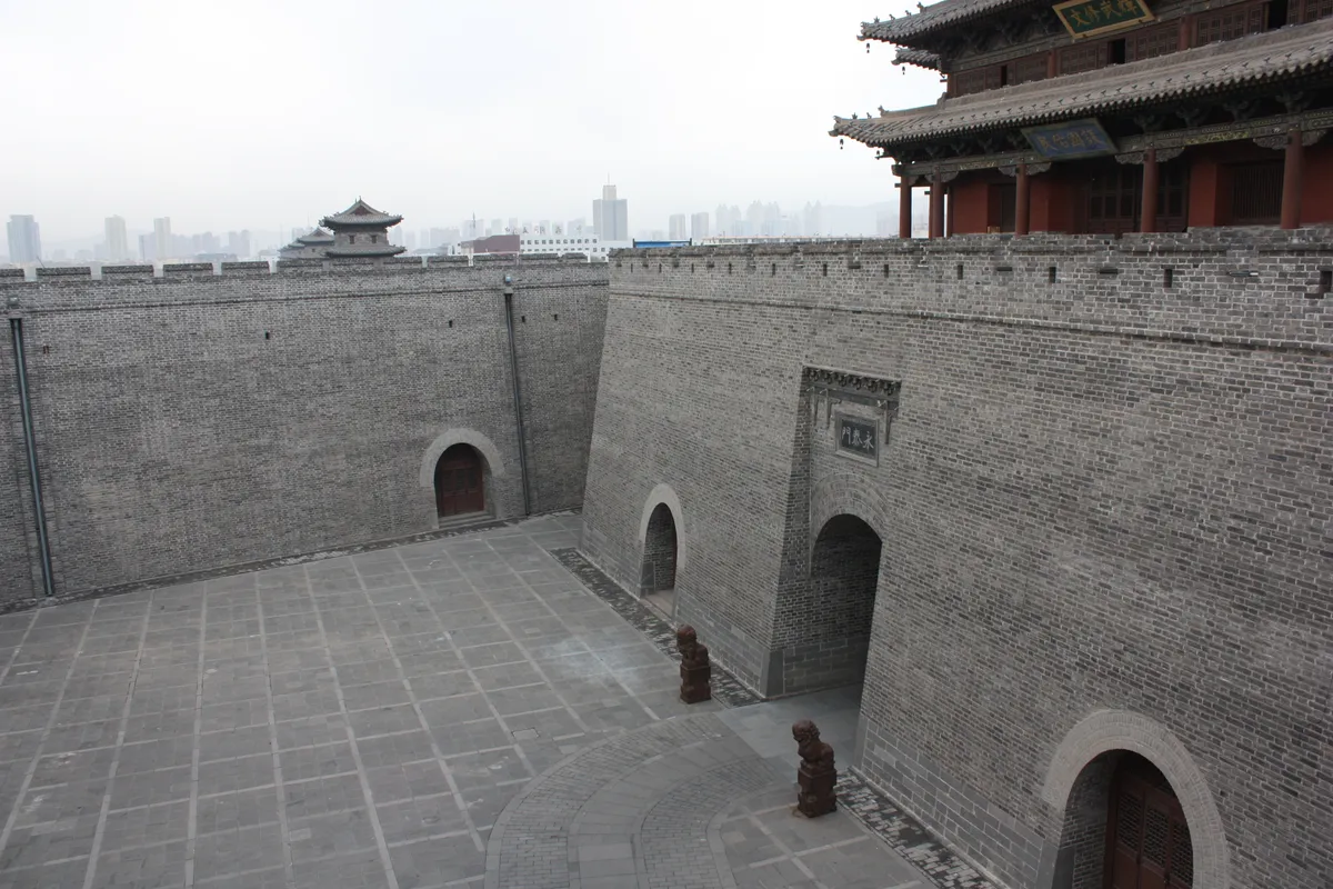 A gate tower and battlements of the rebuilt Datong city wall, with the modern skyline visible behind