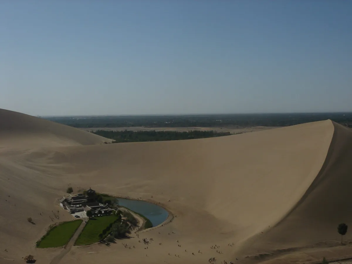 Aerial view of the crescent-shaped Crescent Lake oasis surrounded by the Mingsha sand dunes