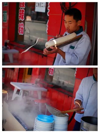 A chef shaving knife-cut noodles from a block of dough directly into a steaming pot at a Datong street stall