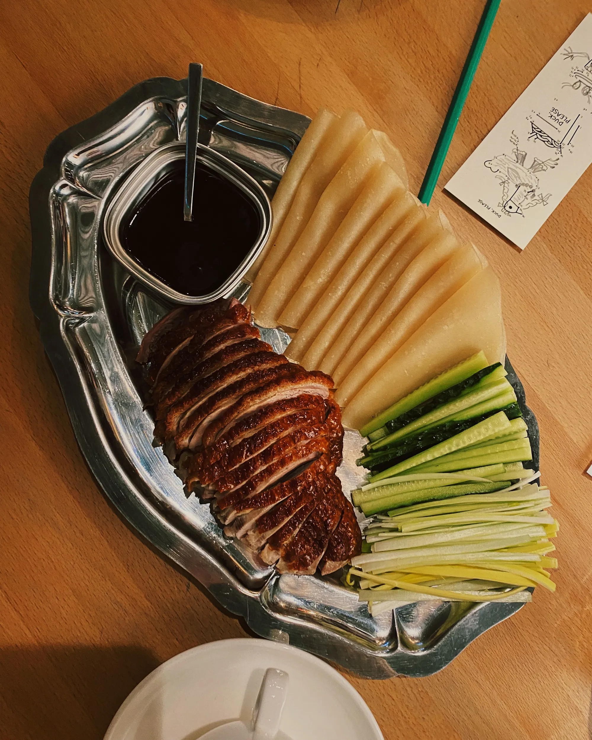 A platter of sliced Peking duck with pancakes, cucumber, scallion, and sauce