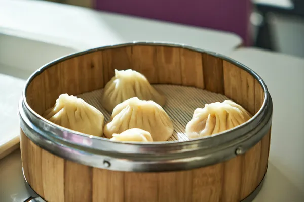 Freshly steamed dumplings in a bamboo steamer basket