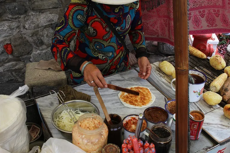 A Dali street vendor spreading sauce on a grilled erkuai rice sheet