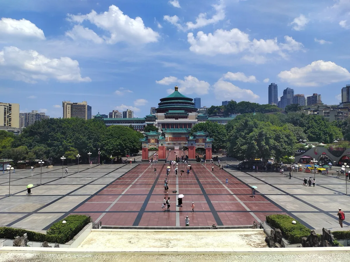 The Great Hall of the People's tiered teal roofs rising above People's Square in Chongqing