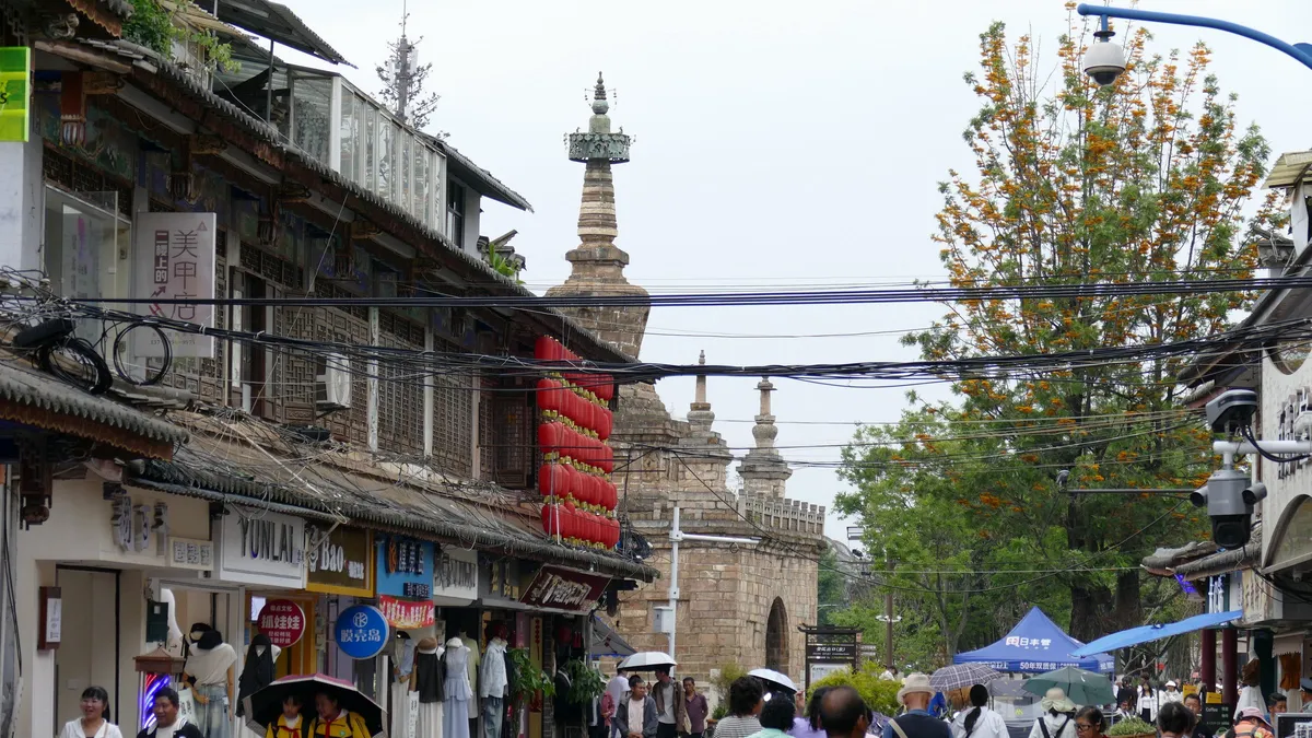A pedestrian street in Guandu Ancient Town, Kunming, with an old stone pagoda visible above the shops