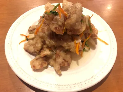 A plate of crispy sweet-and-sour guobaorou pork strips garnished with carrot and scallion