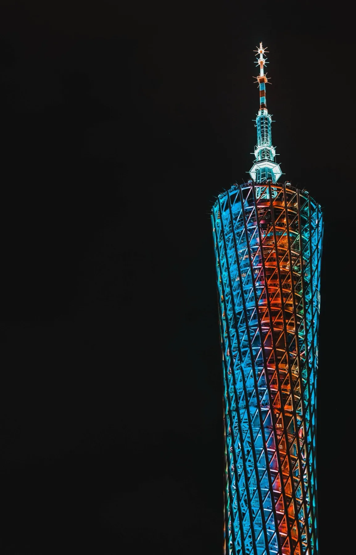 The Canton Tower illuminated in blue and orange lights against a night sky