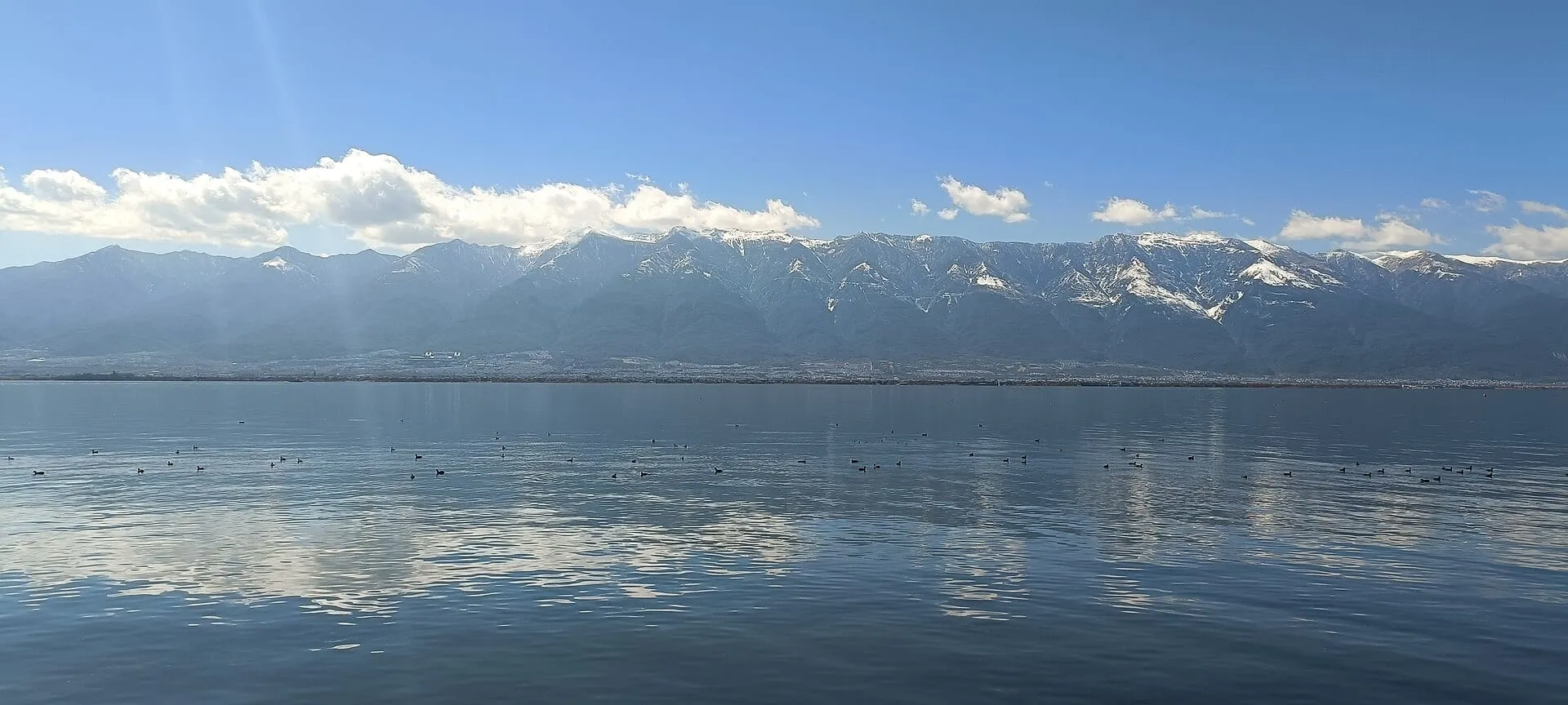 Erhai Lake reflecting snow-streaked Cangshan under a blue sky