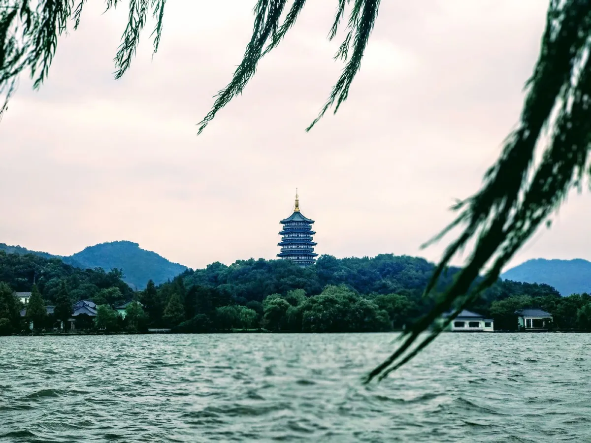 Leifeng Pagoda rising above the treeline on West Lake, framed by willow branches