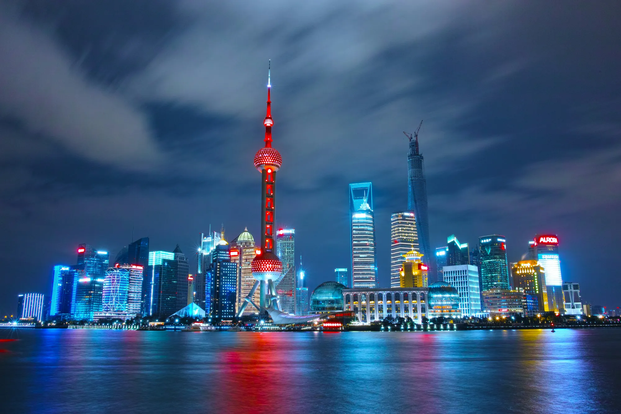 The Pudong skyline and Oriental Pearl Tower lit up at night across the Huangpu River