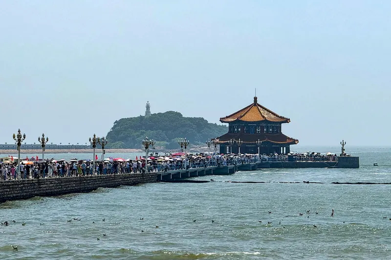 Crowds walking Zhanqiao Pier toward its double-roofed pavilion in Qingdao