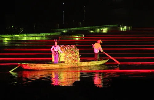 A performer on a decorated boat lit by colorful stage lights during the Impression Liu Sanjie night show