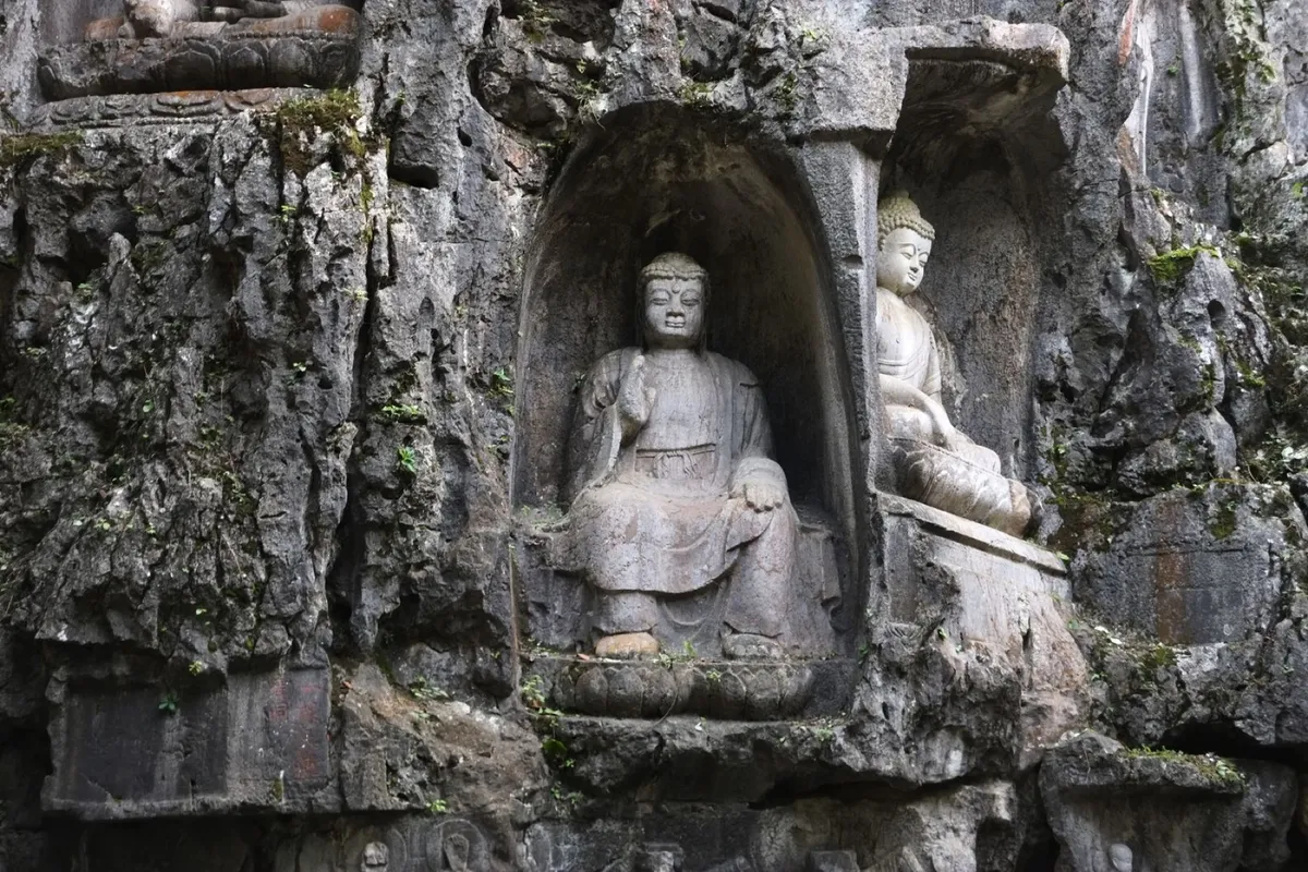 Weathered Buddhist rock carvings in niches cut into the cliff face at Feilai Peak