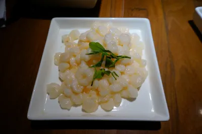 A plate of pale stir-fried Longjing shrimp garnished with tea leaves