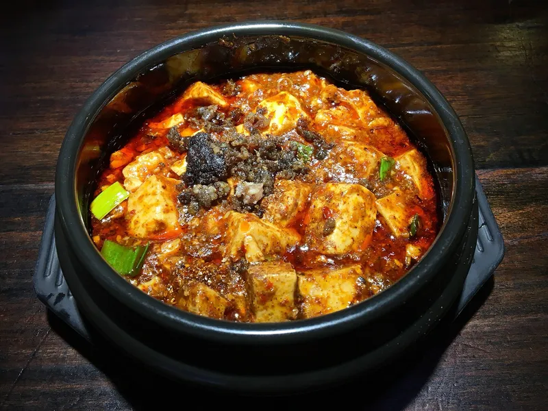 A clay pot of mapo tofu in red chili oil topped with minced meat