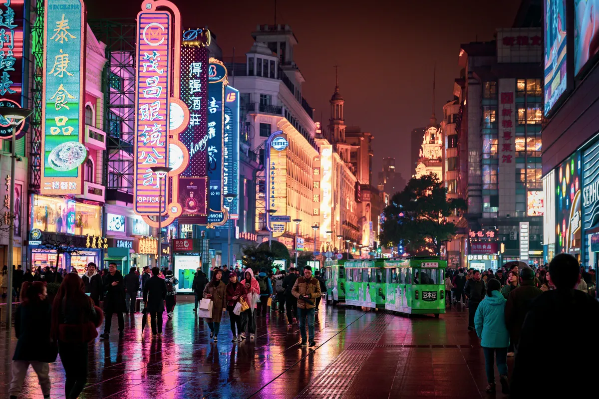 Crowds and neon signage along Nanjing Road at night in the rain