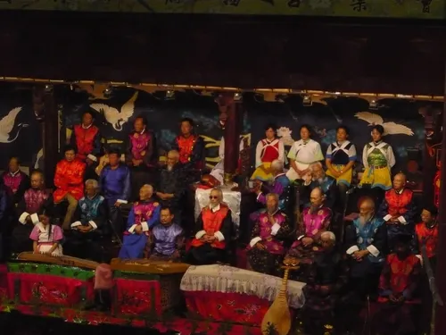 Elderly Naxi musicians in formal robes performing traditional instruments on stage in Lijiang