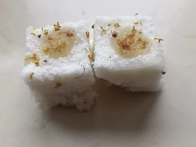 Two pieces of white osmanthus cake studded with small golden flowers