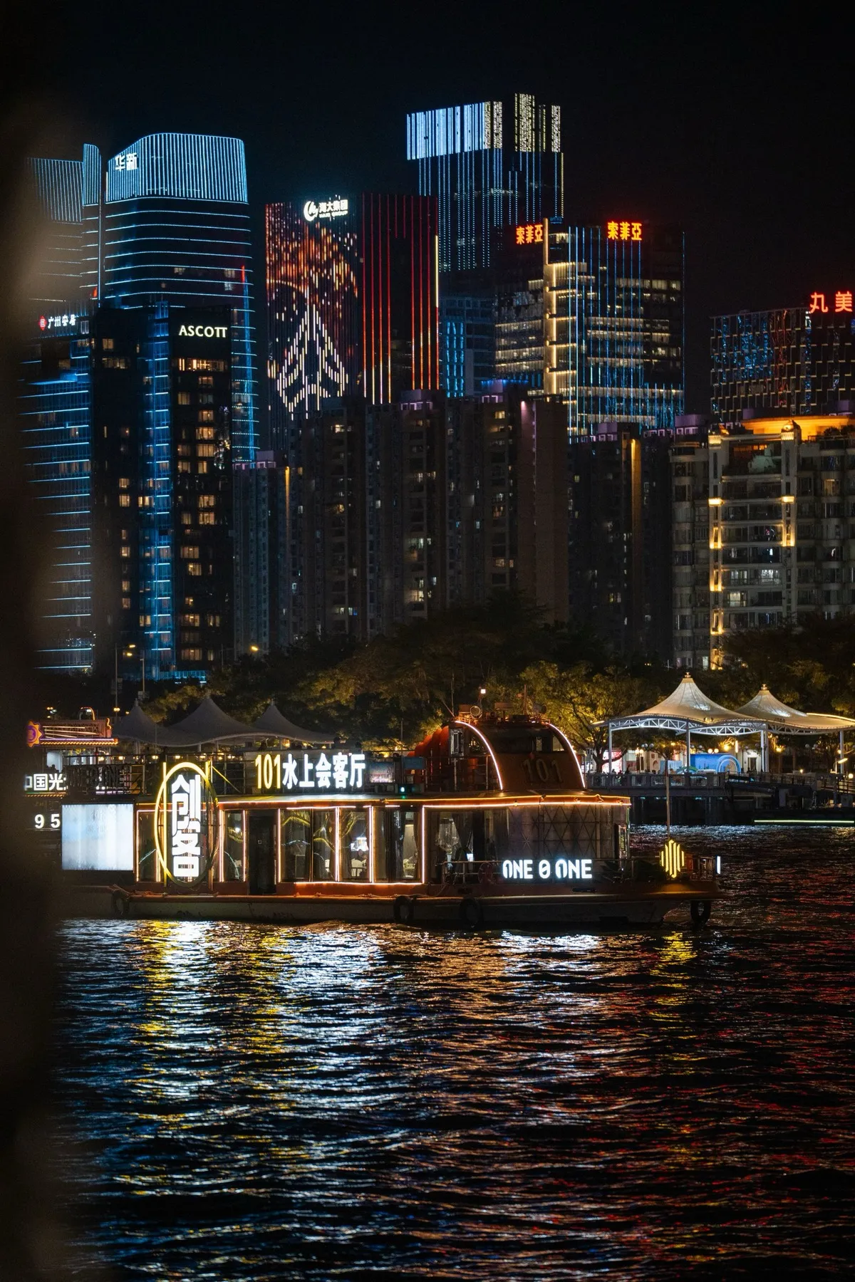 An illuminated cruise boat on the Pearl River with Guangzhou's lit-up skyscraper skyline behind it
