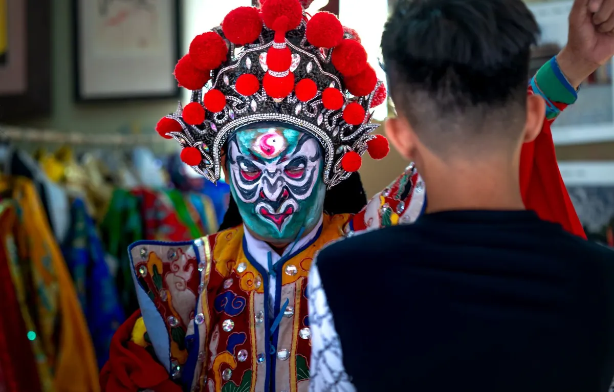 A Peking opera performer in elaborate costume and painted face on stage