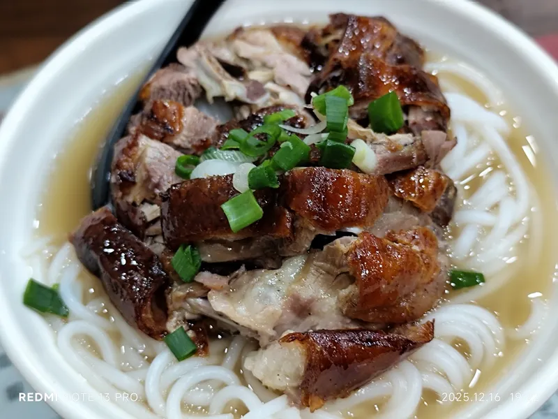Chopped roast goose with dark crisp skin served over noodles in broth