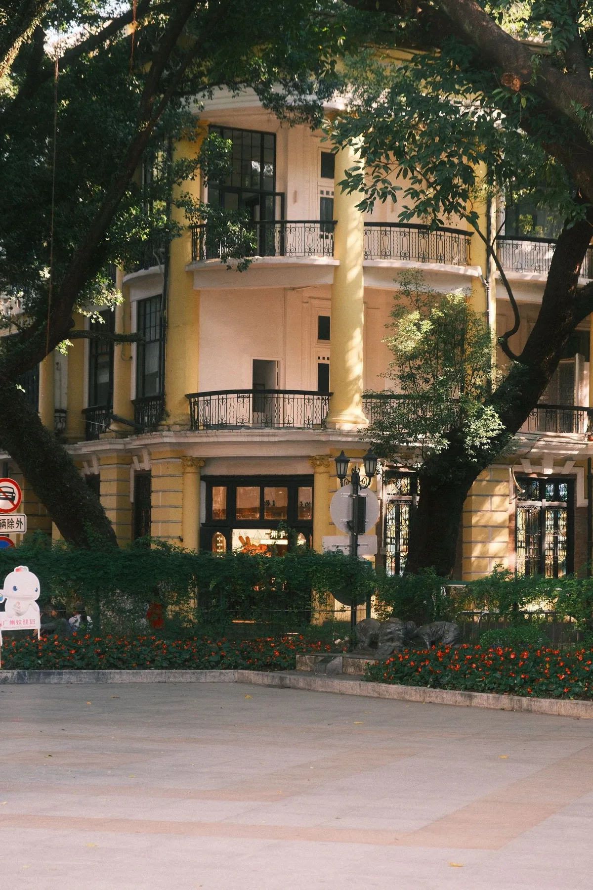 A colonial-era yellow building with balconies surrounded by trees on Shamian Island