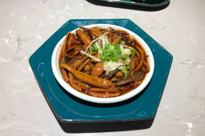 Shredded stir-fried eel in dark sauce topped with ginger and scallion