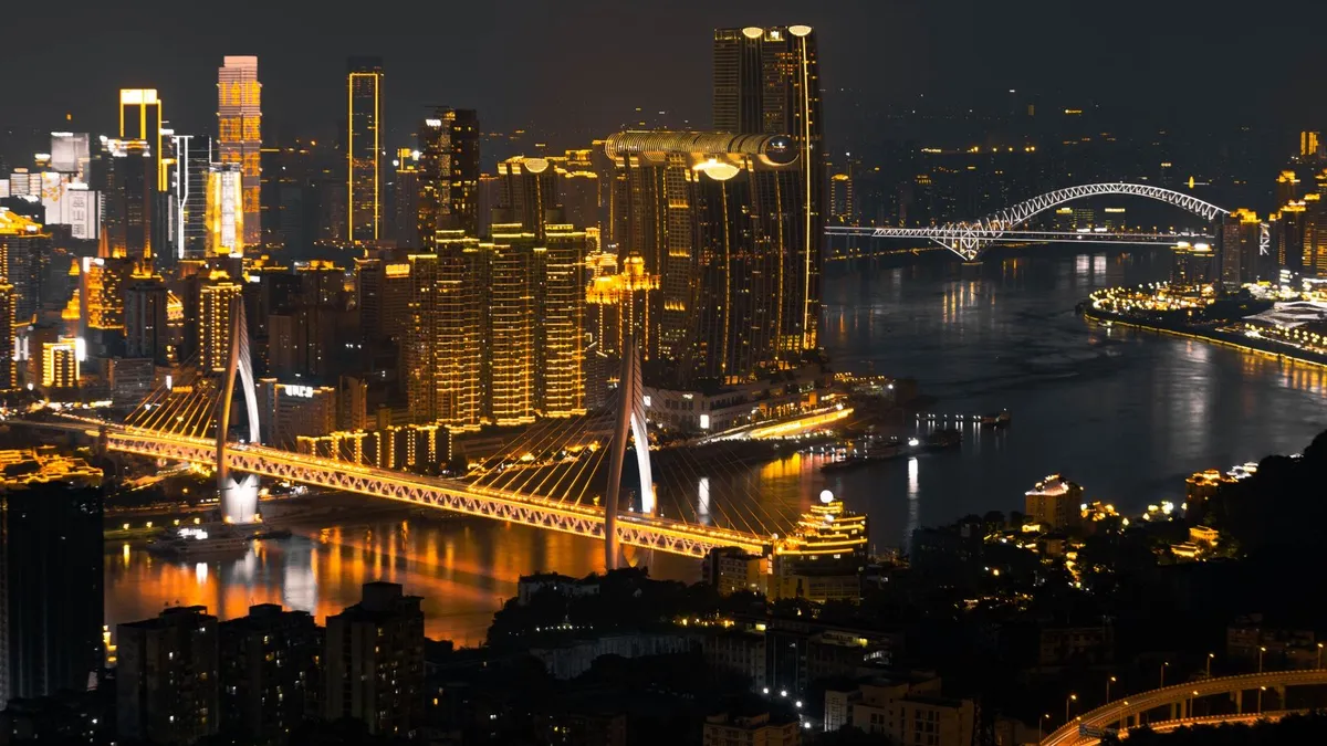 Chongqing's illuminated skyscraper skyline and bridge reflecting on the river at night