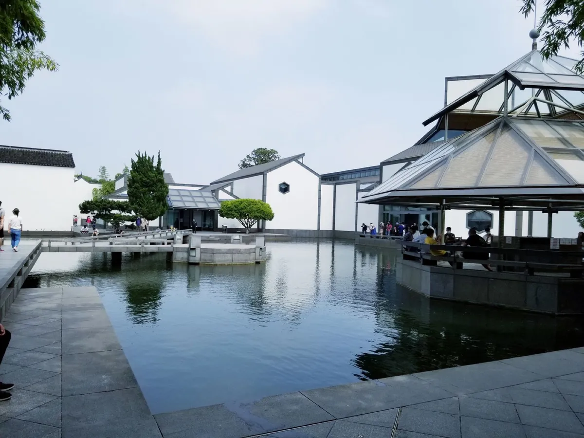 The geometric grey-and-white modern architecture of Suzhou Museum reflected in its courtyard pond