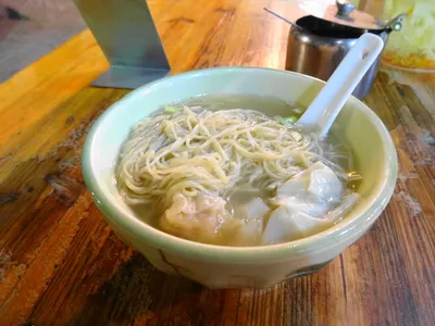 A bowl of wonton noodle soup with thin egg noodles and pork-shrimp wontons