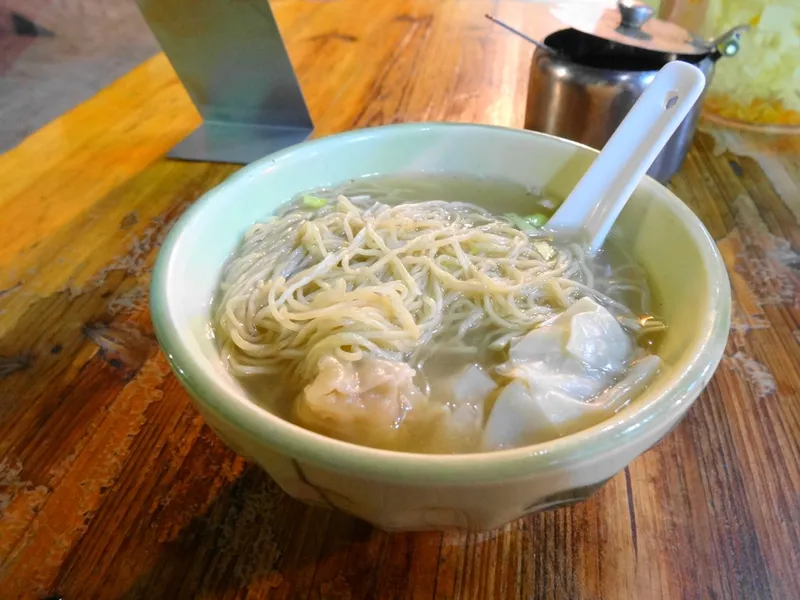 A bowl of wonton noodle soup with thin egg noodles and pork-shrimp wontons
