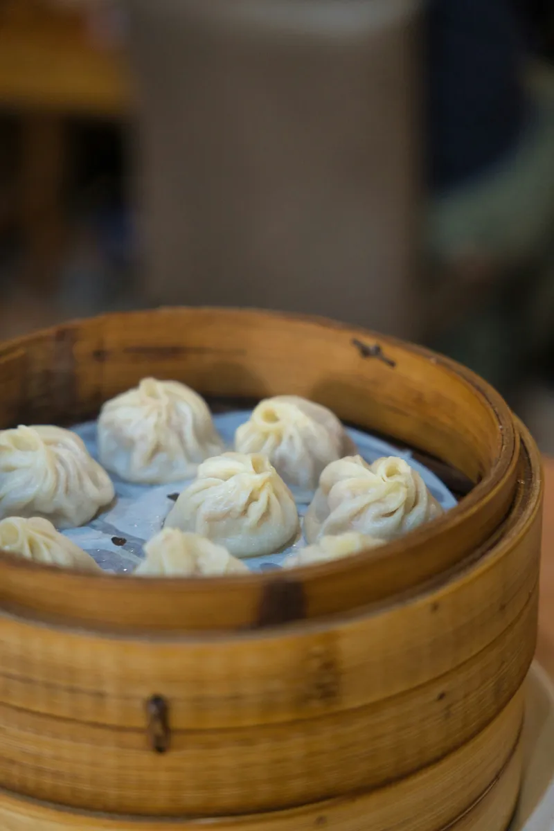 Soup dumplings pleated and steamed in a bamboo basket