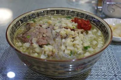 A bowl of yangrou paomo with crumbled bread, lamb, glass noodles, and chili paste
