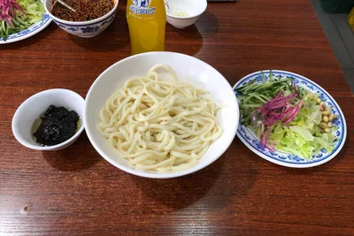 Zhajiang noodles served the classic way — noodles, dark fried sauce, and shredded vegetable sides, at a Beijing noodle shop
