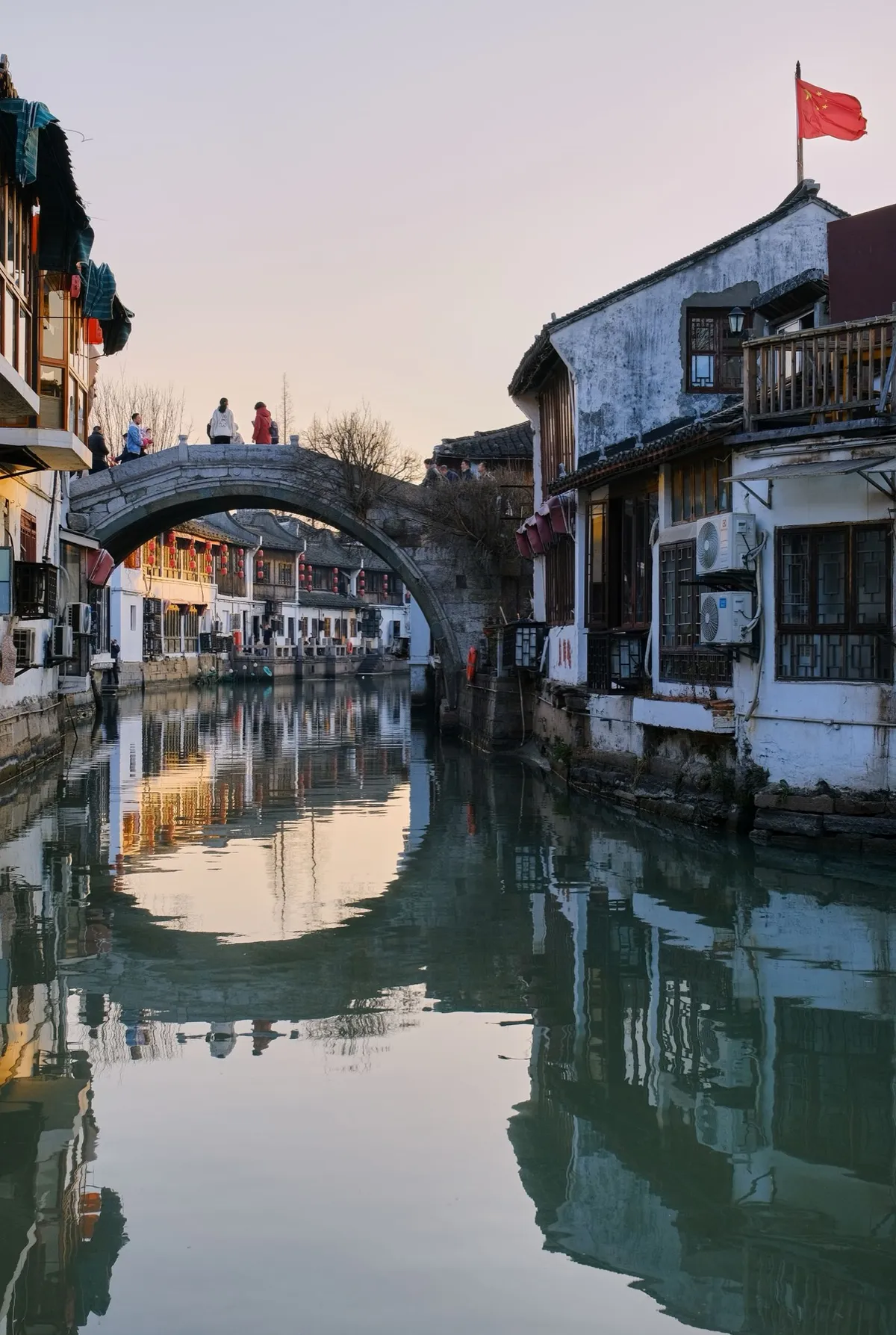 An arched stone bridge over a canal reflecting whitewashed houses at Zhouzhuang water town